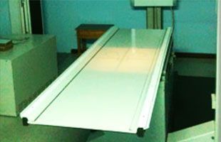 Una máquina de rayos X está en una habitación al lado de una mesa.