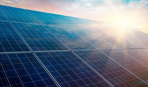 Des panneaux solaires dans un champ ensoleillé, la lumière vive du soleil se reflétant sur des réseaux photovoltaïques bleus.