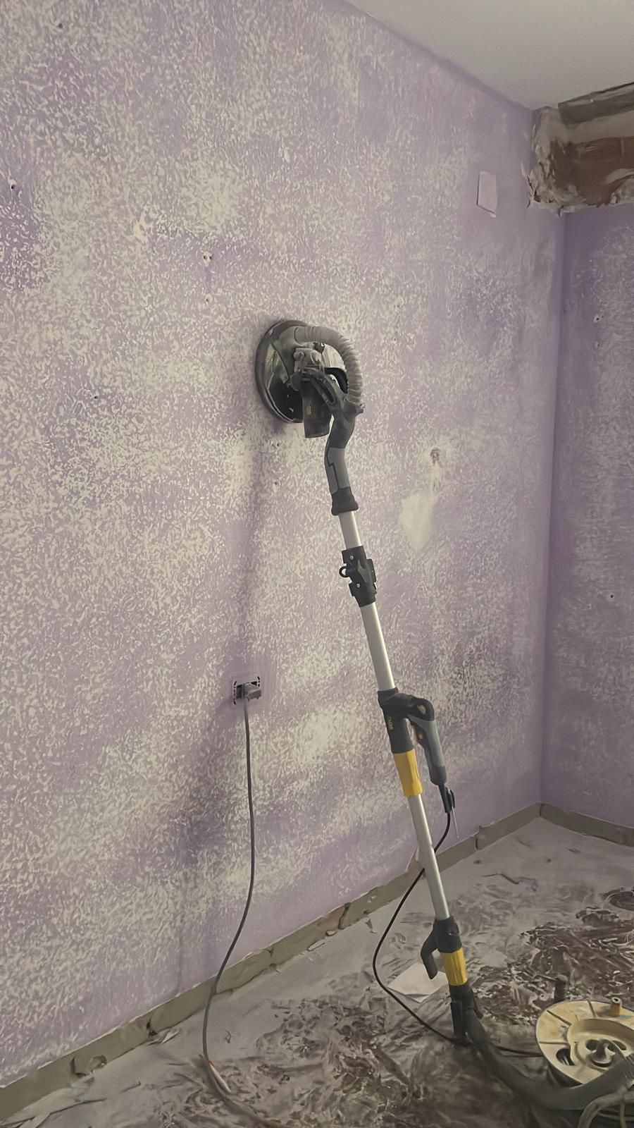 Una lijadora está sentada en el suelo en una habitación al lado de una pared.