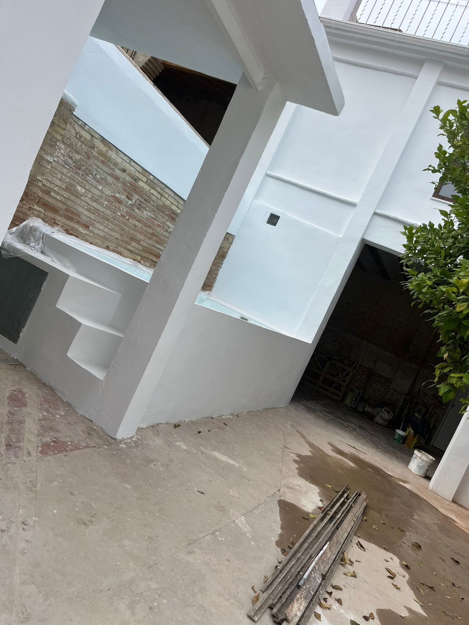 Se está construyendo un edificio blanco con una pared de ladrillo.