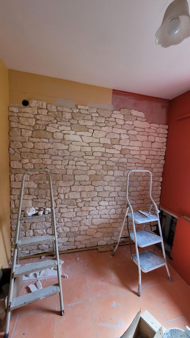 Chambre avec mur d'accent en pierre en construction, échelles et murs rouges/jaunes.