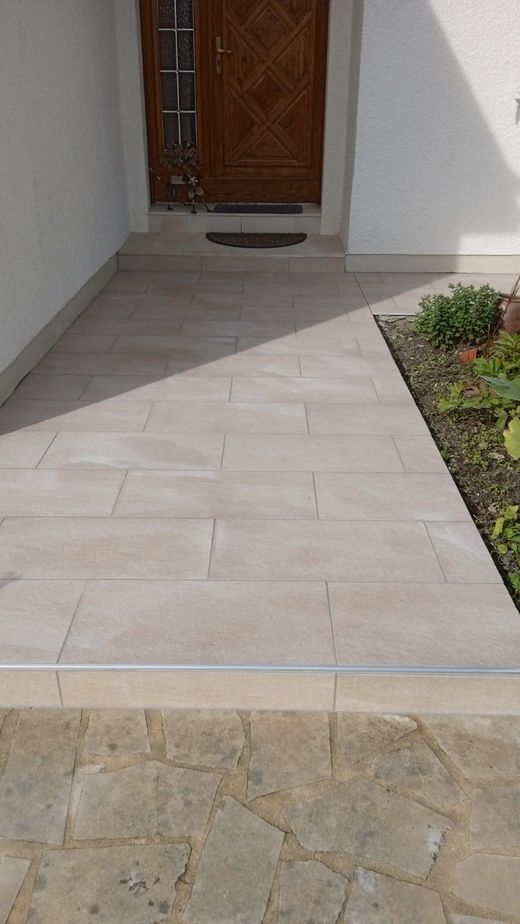 Une allée carrelée menant à la porte d'entrée d'une maison.