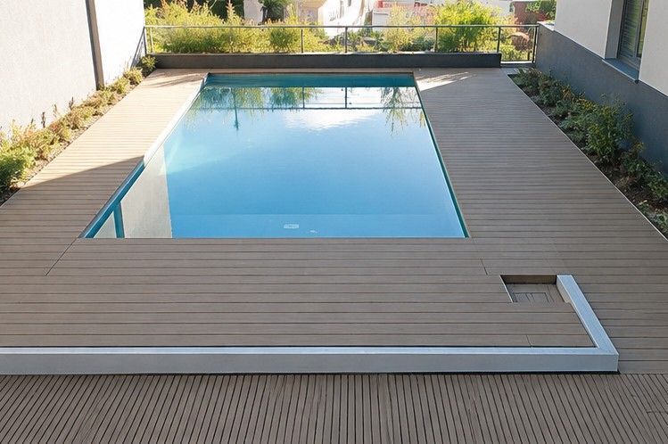 Patio moderno con piscina rectangular a nivel del suelo y tarima de madera alrededor