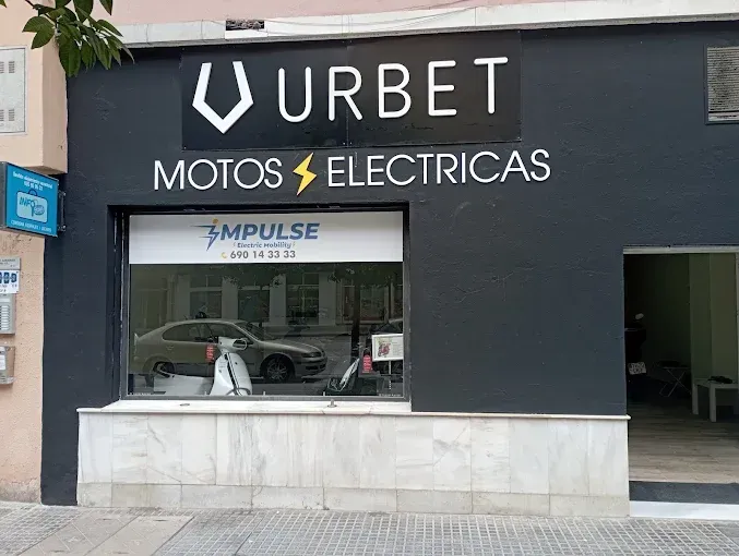 Fachada de una tienda con un letrero que dice “URBET MOTOS ELÉCTRICAS” y una entrada abierta.