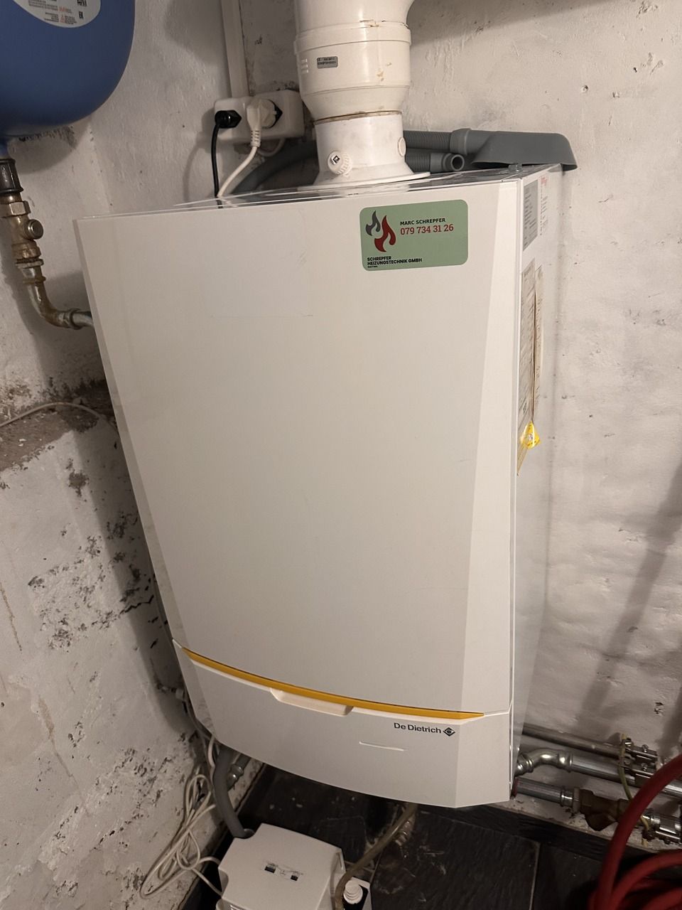 In einem Zimmer hängt ein weisser Heizkessel an der Wand. Foto von der Schrepfer Heizungstechnik GmbH