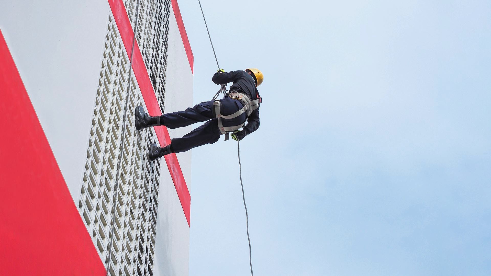 Un hombre está subiendo por el costado de un edificio.