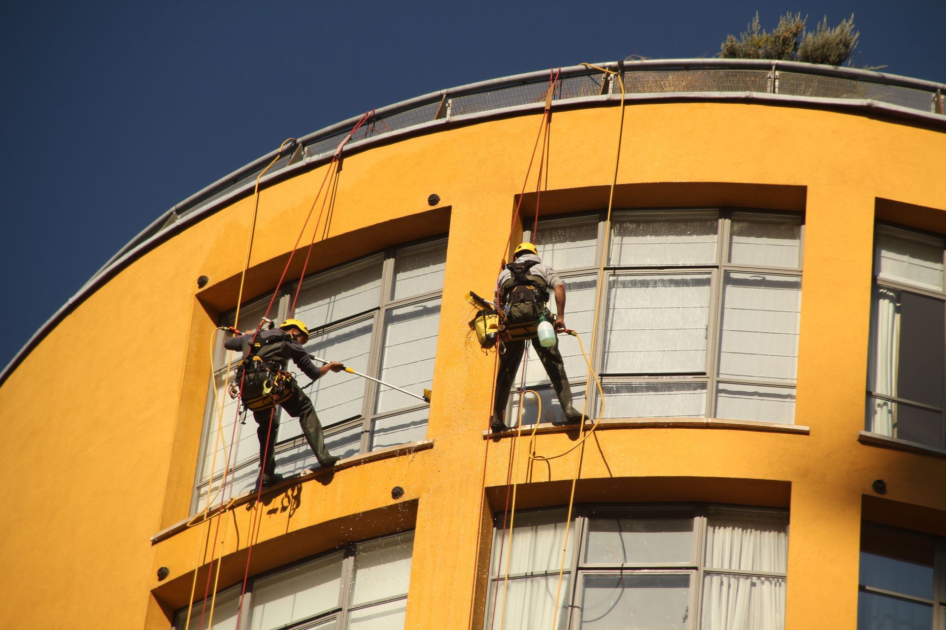 Dos hombres están trepando por el costado de un edificio.