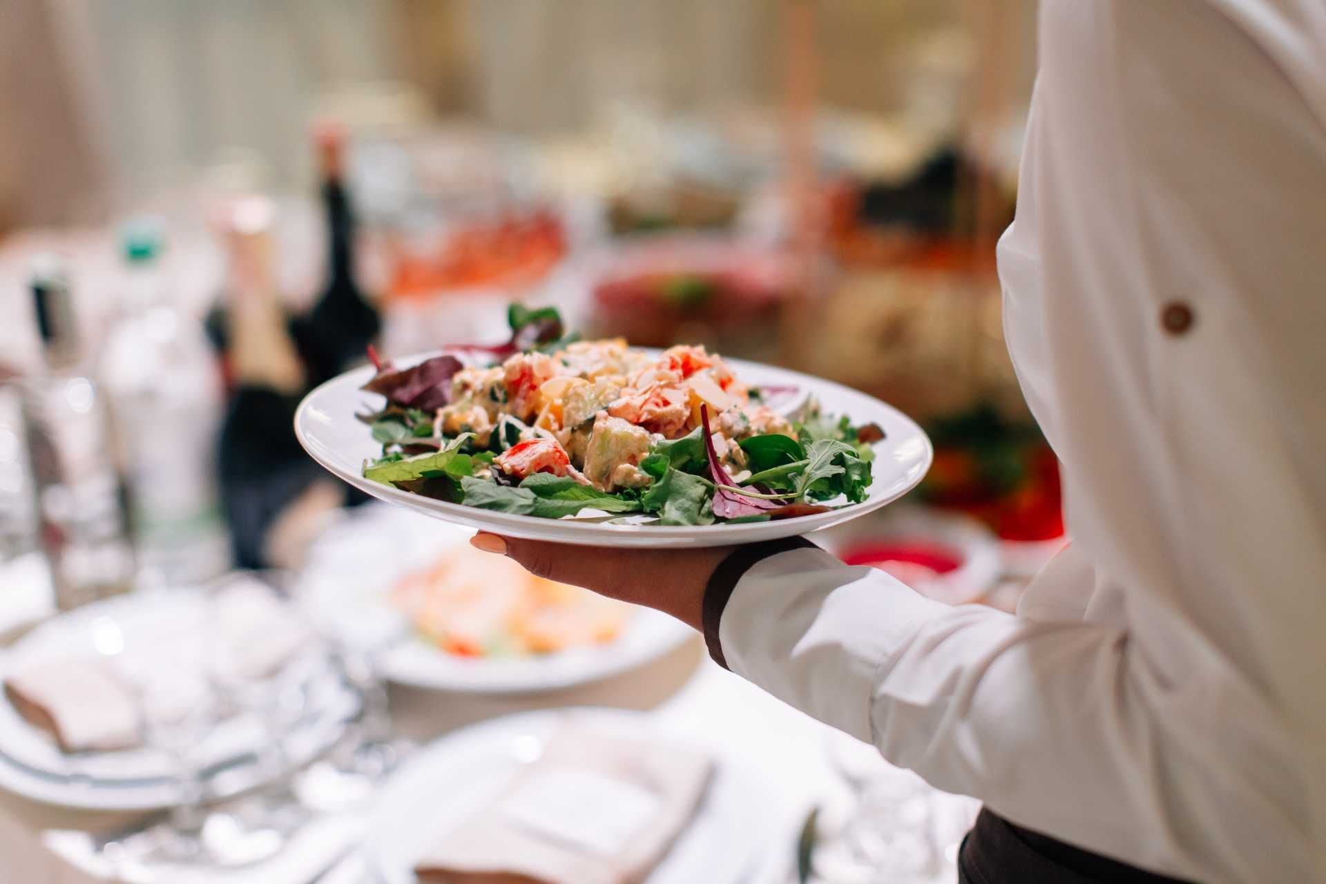 une serveuse tient une salade