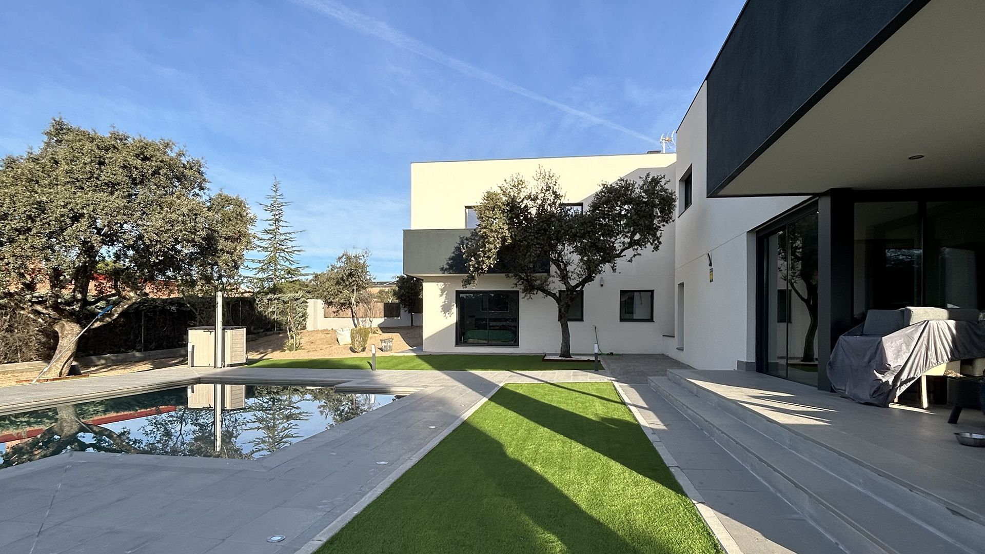 Una gran casa blanca con piscina en el patio trasero.