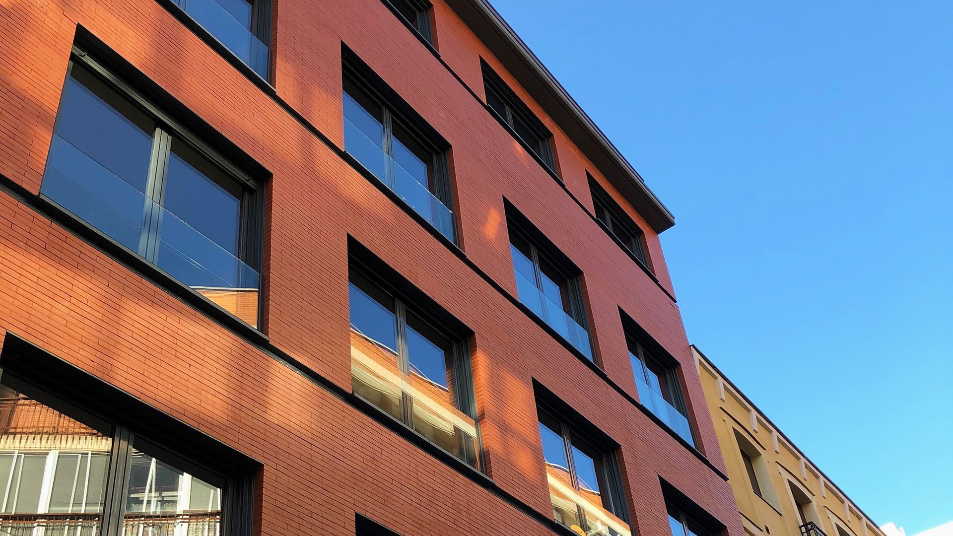 Un edificio de ladrillo con muchas ventanas y un cielo azul al fondo.