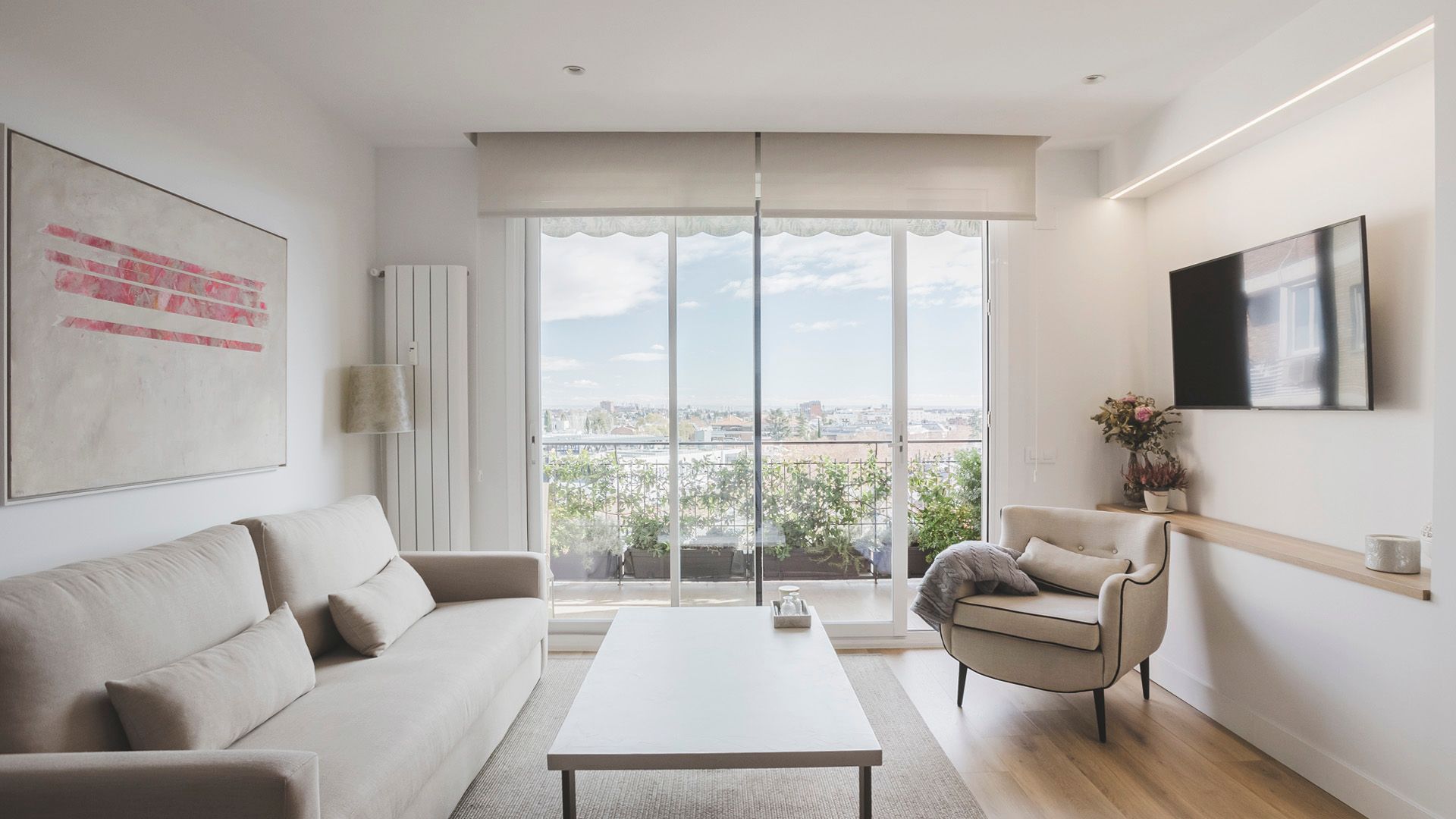 Una sala de estar con sofá, silla, mesa de café y televisión.