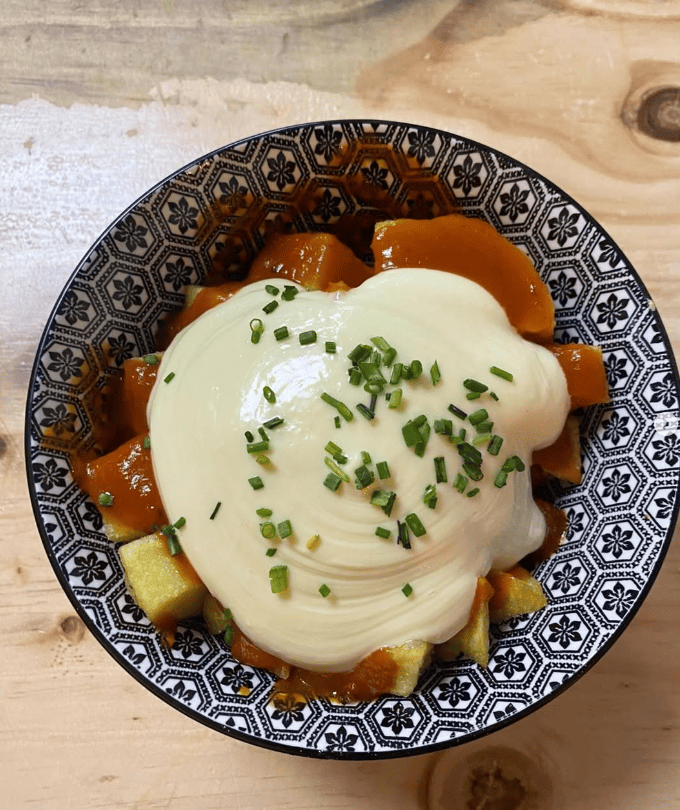 Un tazón de comida con salsa y queso sobre una mesa de madera.