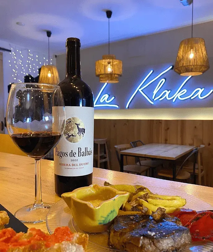 Una botella de vino está sobre una mesa al lado de una copa de vino.