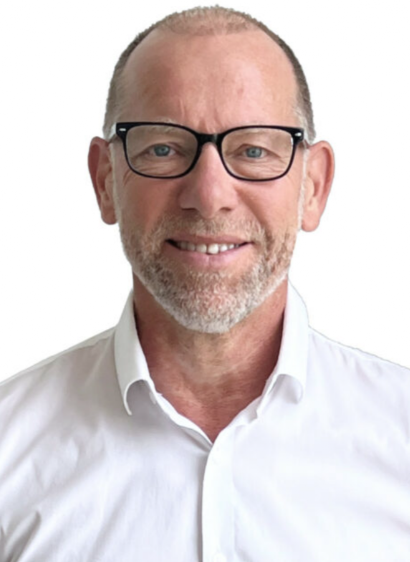 Ein Mann mit Brille und weißem Hemd lächelt in die Kamera