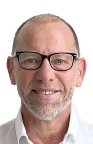 Ein Mann mit Brille und weißem Hemd lächelt in die Kamera