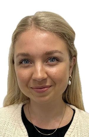 Eine Frau mit blonden Haaren und blauen Augen lächelt in die Kamera.