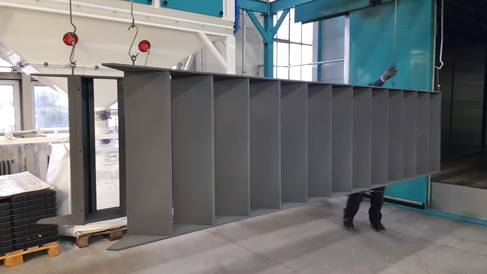 In einer Fabrik wird eine große Metallkonstruktion lackiert.