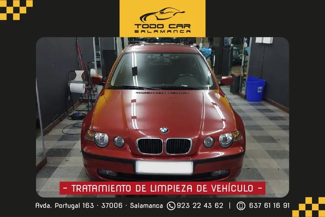 Red BMW car in a garage with text "TRATAMIENTO DE LIMPIEZA DE VEHICULO" and company info.