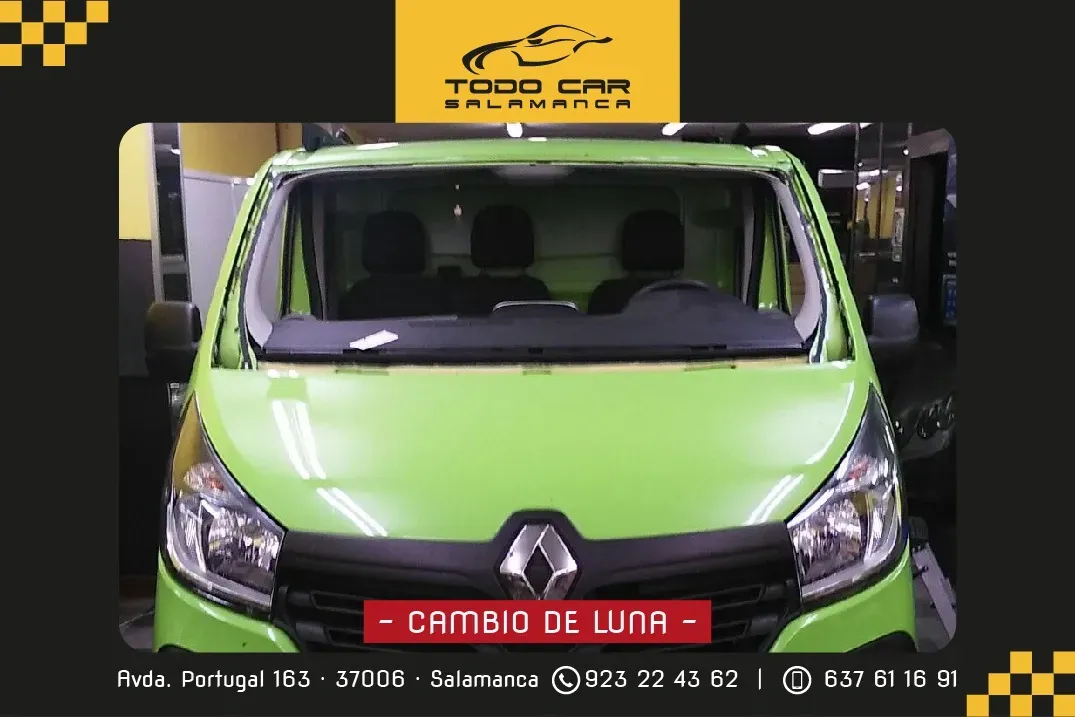 Furgoneta Renault verde con cartel de cambio de parabrisas. Logotipo de la tienda al fondo.