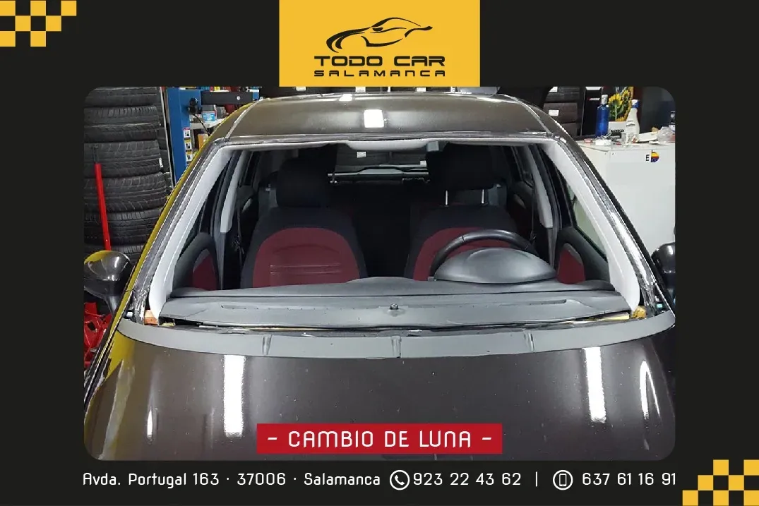 Automóvil con parabrisas removido dentro de un taller mecánico; se muestra el texto "Cambio de luna".