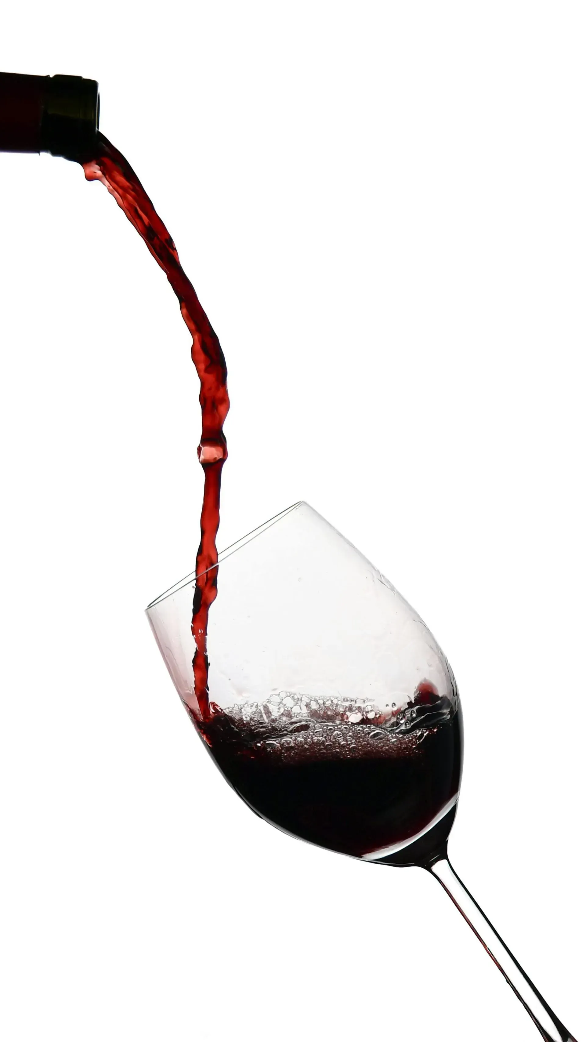 Vino tinto siendo vertido en una copa de vino inclinada sobre un fondo blanco.