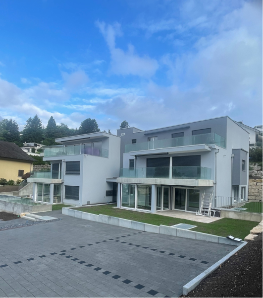 Haus im Bau, weisse Außenverkleidung, Gerüst, blaue Fenster, klarer Himmel.
