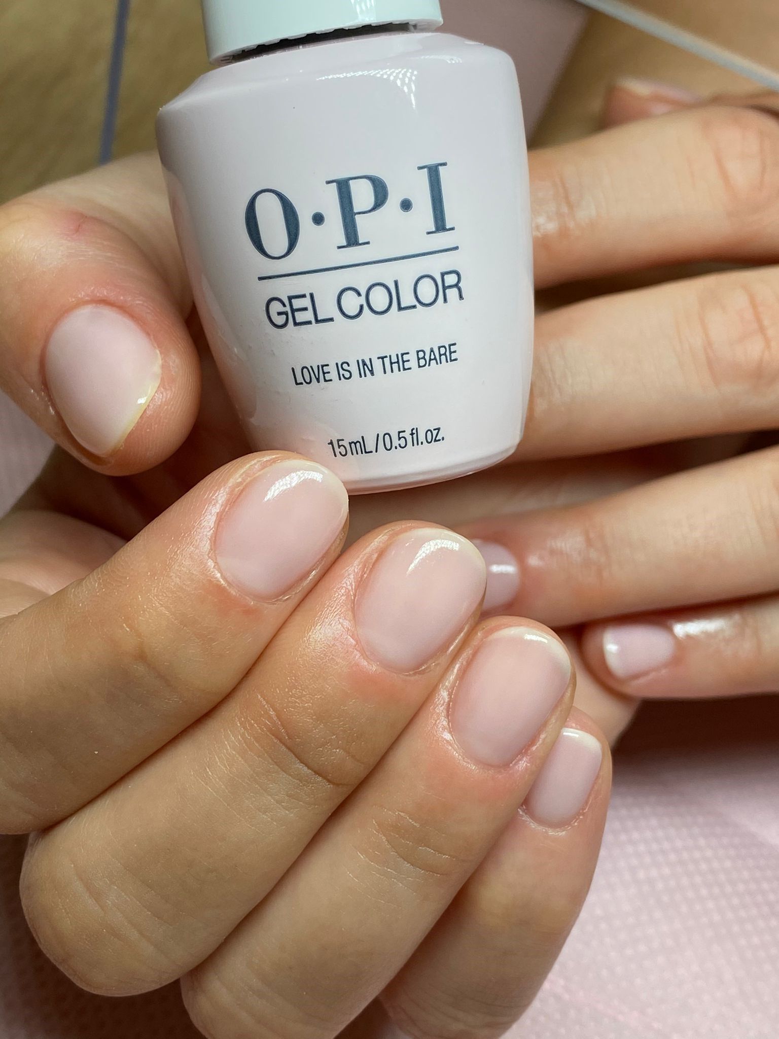 Una persona tiene in mano una boccetta di gel colorato OPI sulle unghie.