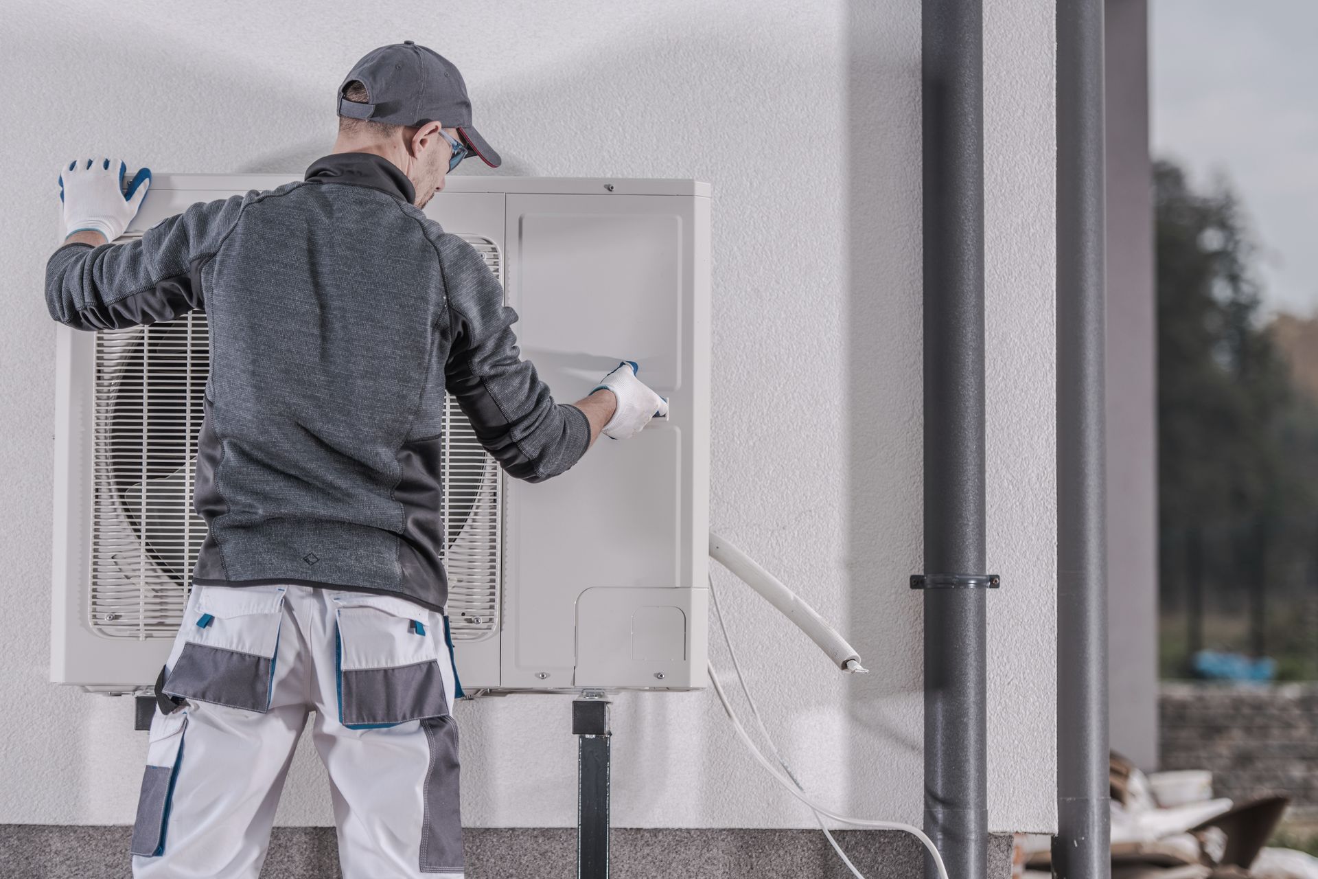 Un ouvrier pulvérise de l'eau dans un boîtier électrique extérieur sur le mur d'un bâtiment.