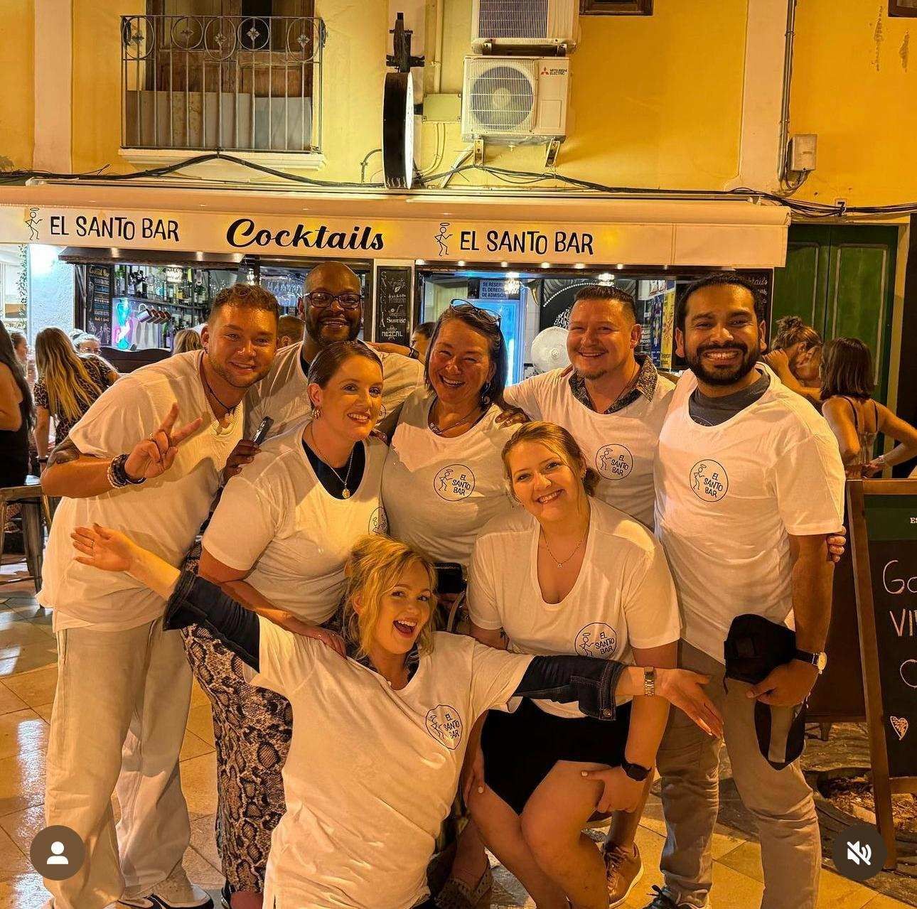 Un grupo de personas posando para una foto frente a un bar de cócteles.