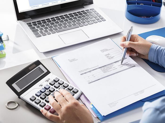 Una persona está usando una calculadora y escribiendo en un trozo de papel.