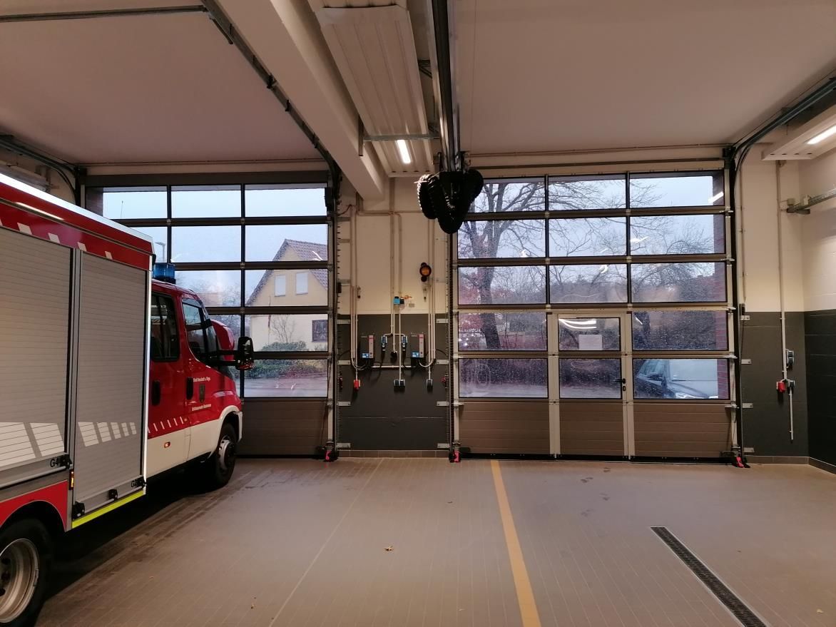 Ein Feuerwehrauto steht in einer Garage mit großem Garagentor.