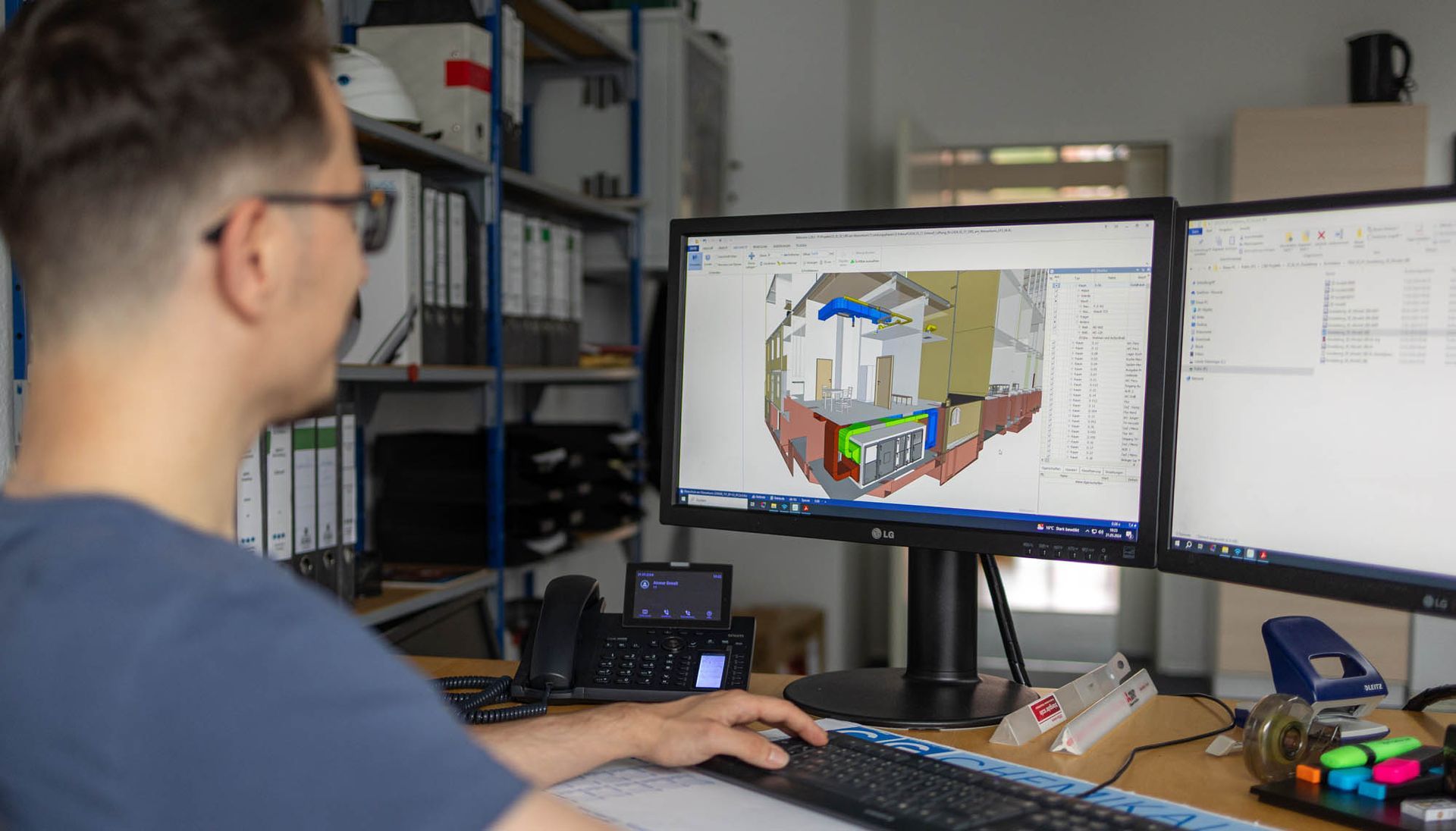 Ein Mann sitzt an einem Schreibtisch und schaut auf einen Computerbildschirm.