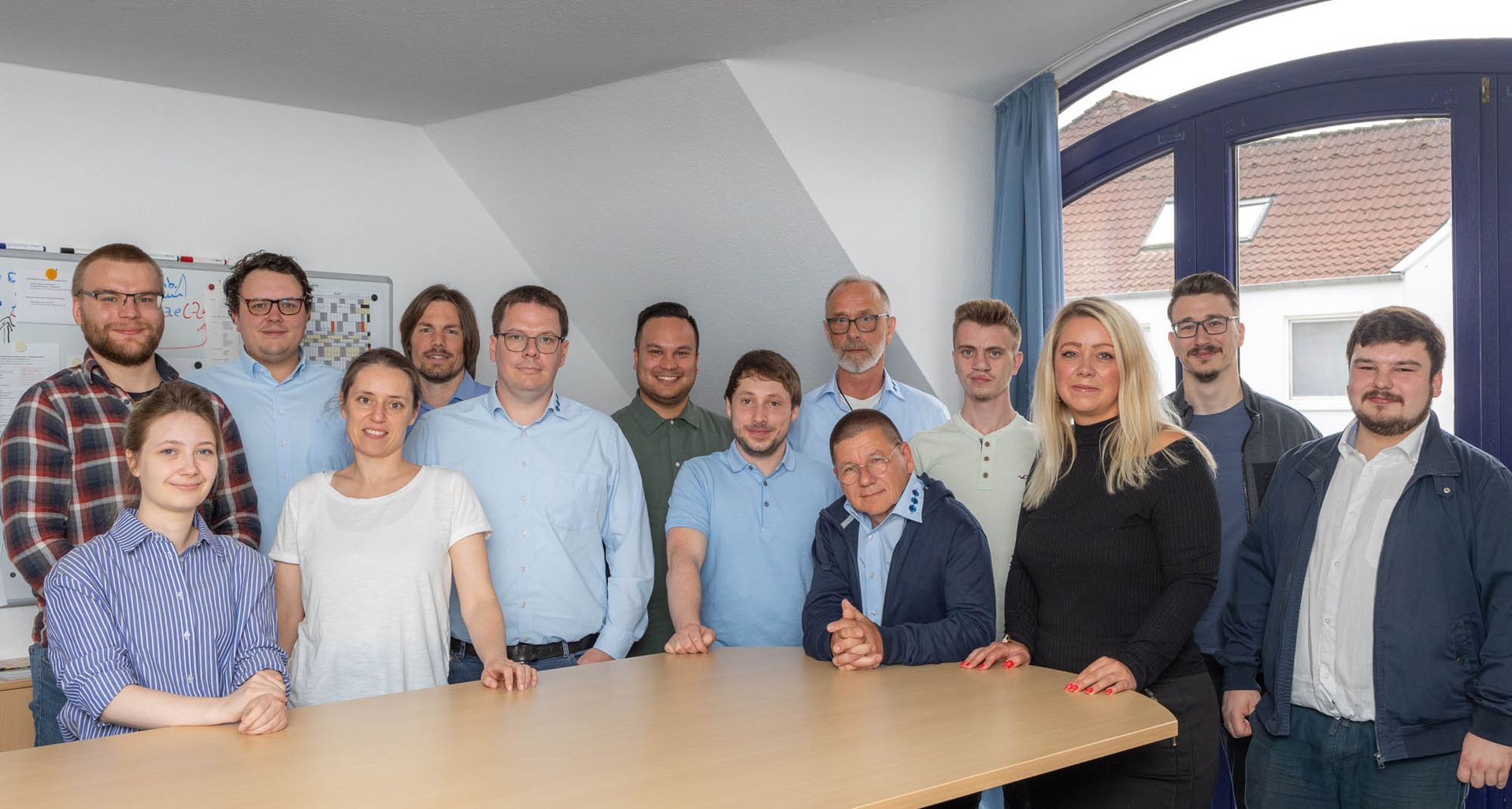 Eine Gruppe von Menschen posiert vor einem Tisch für ein Foto.