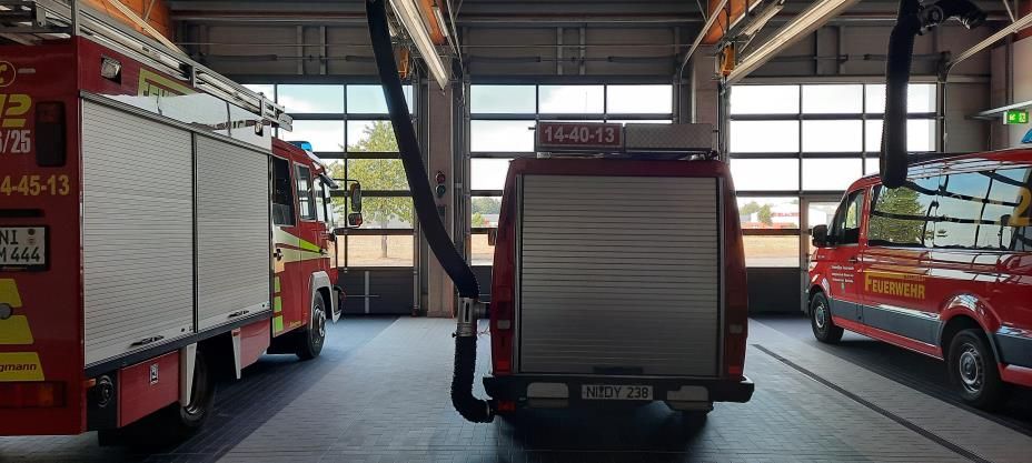In einer Garage steht neben einem Lieferwagen ein Feuerwehrauto.