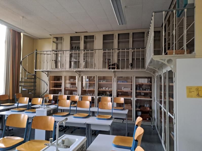 Ein Klassenzimmer mit Tischen und Stühlen und einer Wendeltreppe