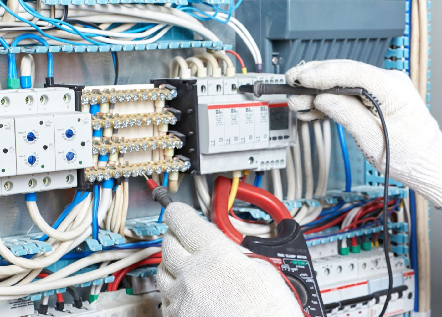 Mains gantées travaillant sur un tableau électrique