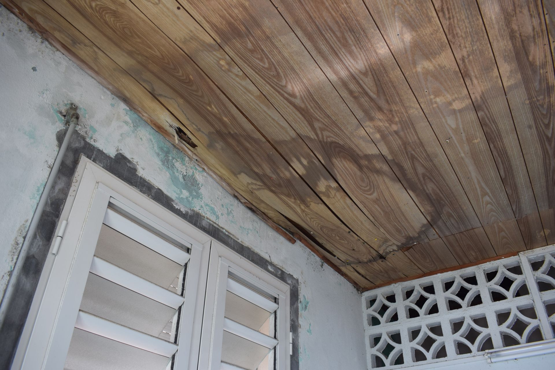 Tache d'humidité sur un plafond en bois et pan de mur abîmé