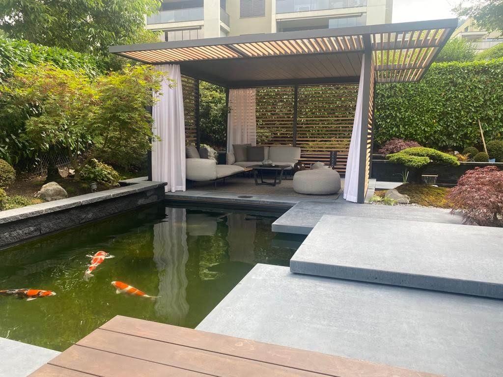 Ein zweistöckiger Aussenbereich mit einem Betongebäude, einer Rasenfläche und einem Gartenbeet.