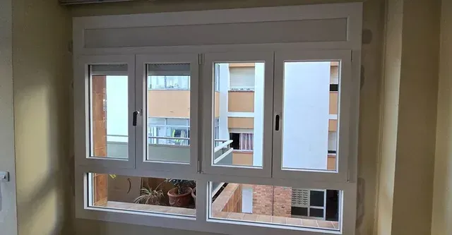 Ventana con marco blanco con vistas a edificios de apartamentos y balcones.