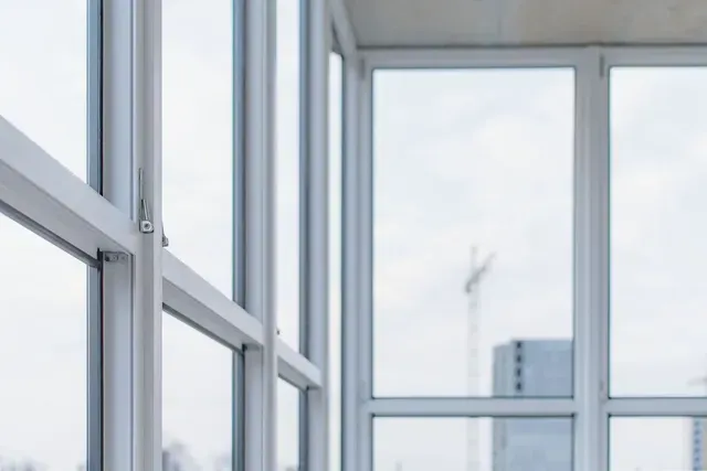 Ventanas modernas de cristal con vistas a un horizonte urbano nublado.