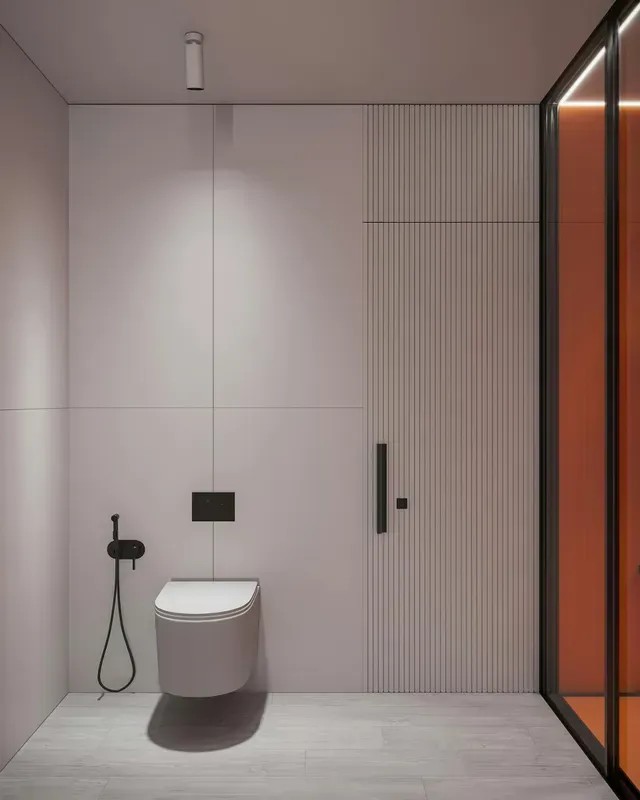 Baño moderno minimalista con inodoro suspendido, grifería negra y ducha de cristal con marco naranja.