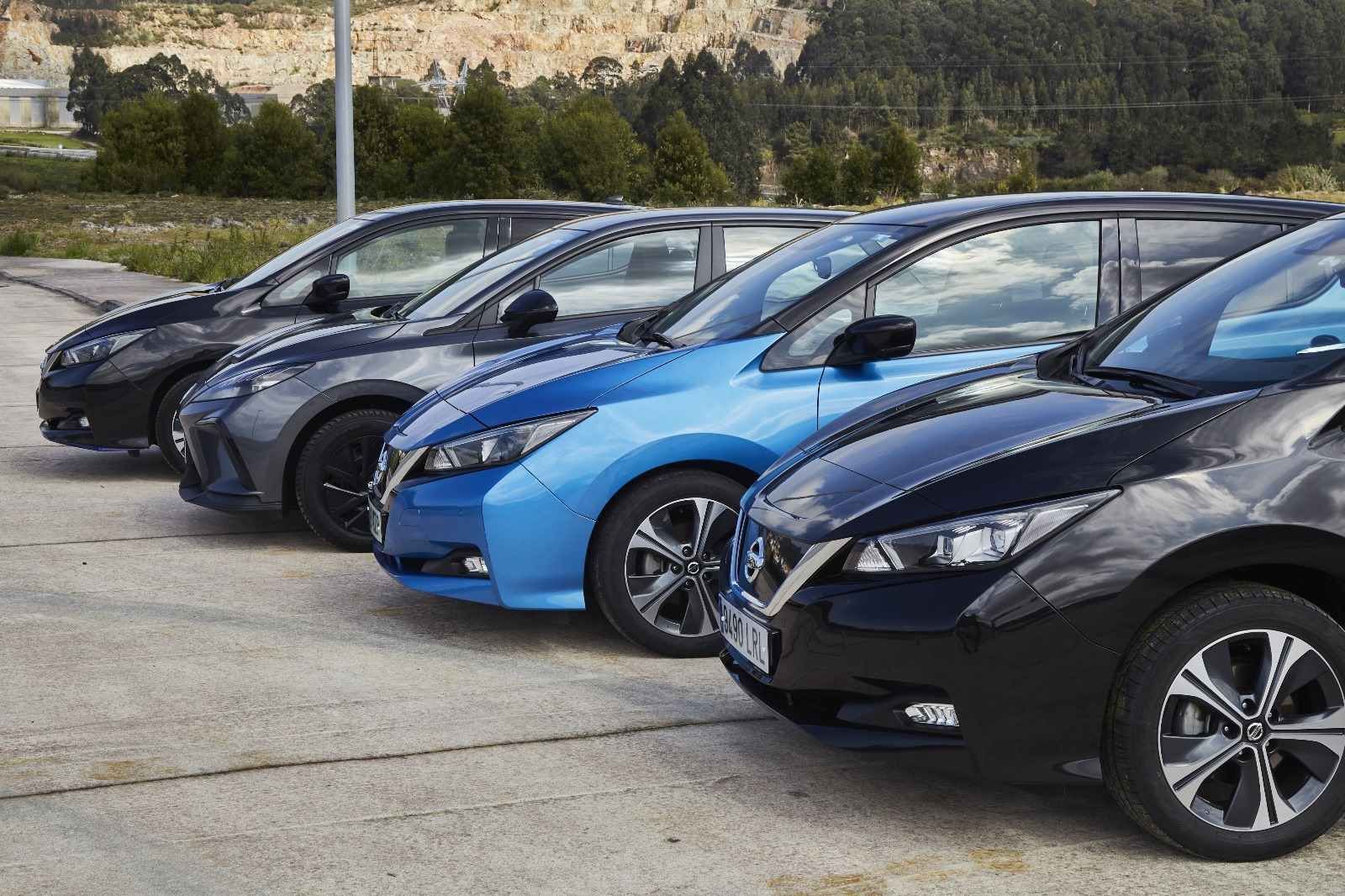 Una fila de coches eléctricos están estacionados en un estacionamiento.