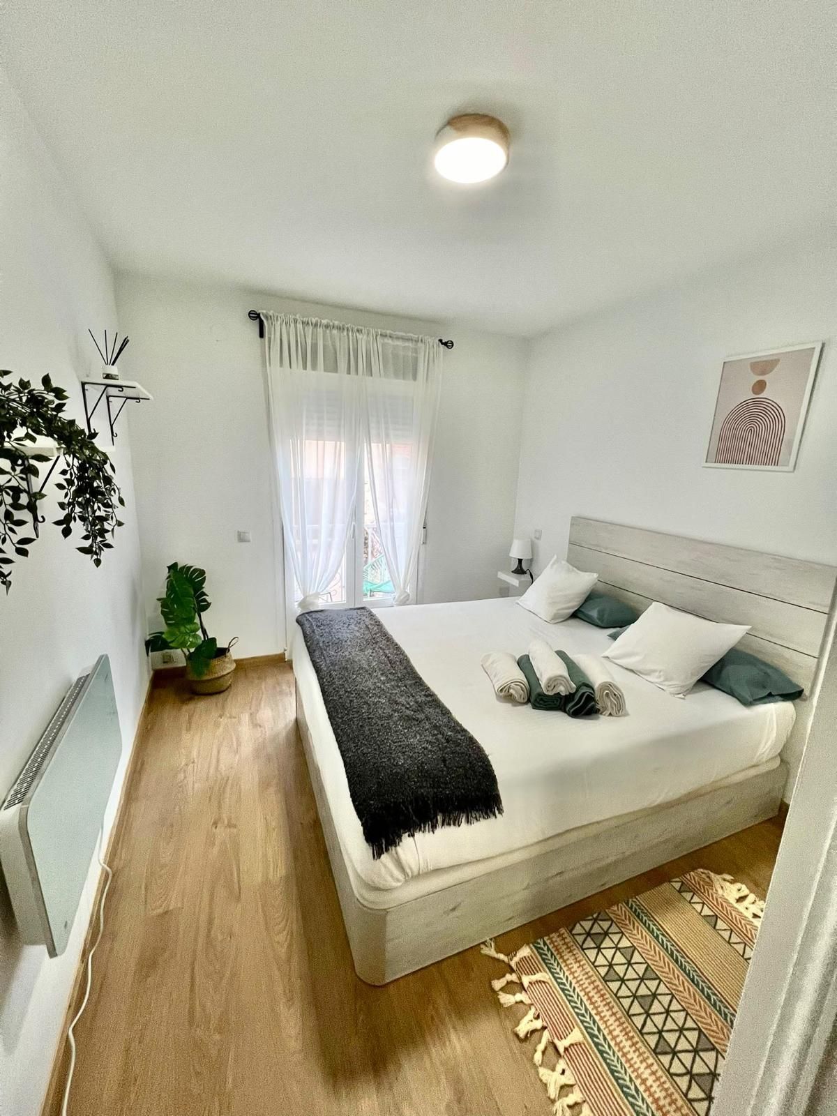 Acogedora sala de estar con sofá modular beige, televisor, alfombra turquesa, mesa de centro, estantes y planta colgante.