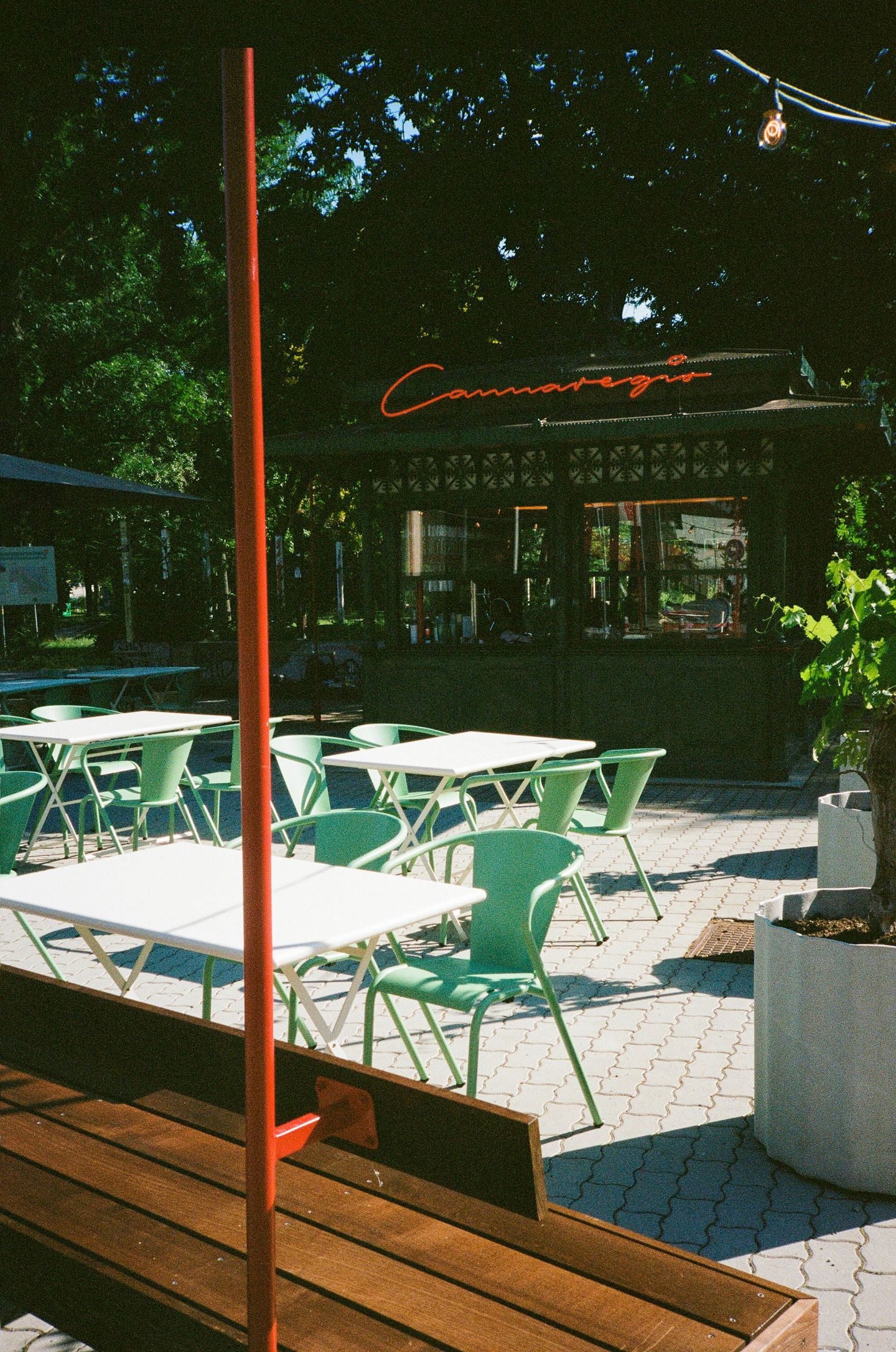 Eine Terrasse mit Tischen und Stühlen mit einem roten Pfosten im Vordergrund