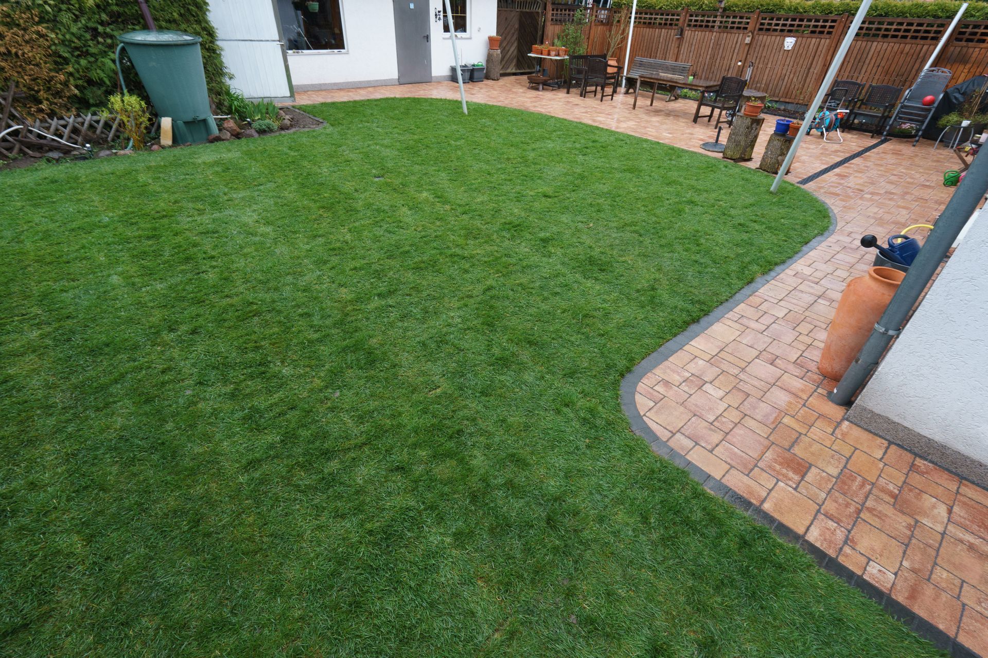 Ein Hinterhof mit einem üppigen grünen Rasen und einem Ziegelweg.