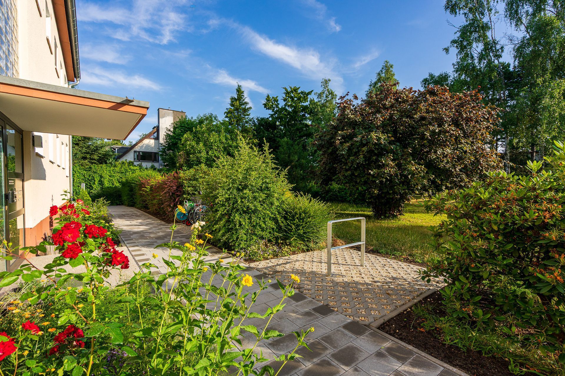 Modern gestalteter Fahrradstellplatz im Eingangsbereich einer Wohnsiedlung – mit funktionalen und stilvollen Fahrradparkern aus Metall. Die Integration in das Gesamtkonzept der Außenanlage sorgt für eine klare Linienführung und unterstützt nachhaltige Mobilität. Begrünte Umgebung und durchdachte Platzierung schaffen eine einladende Atmosphäre für Bewohner und Besucher