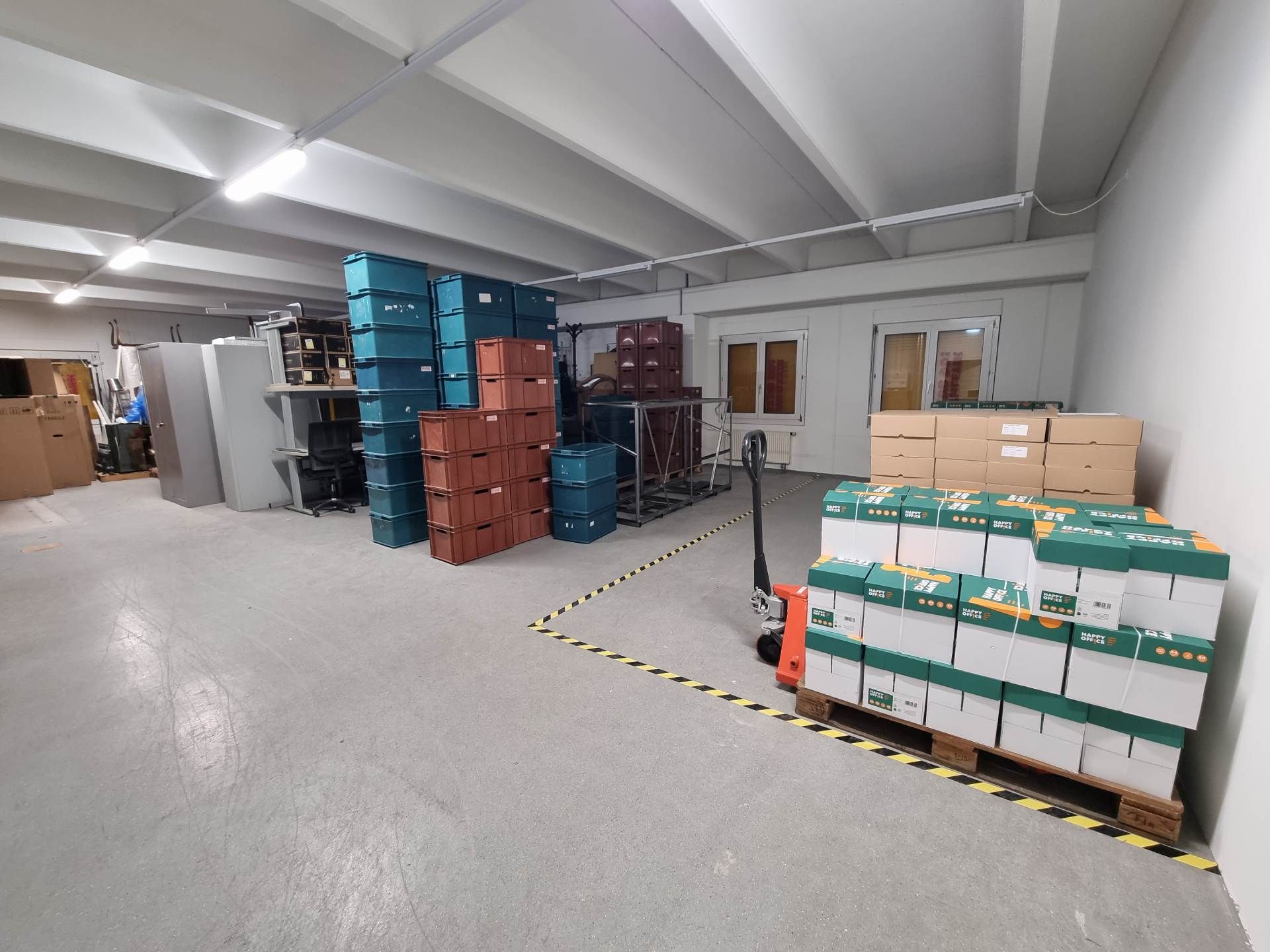 Scatoloni accatastati in una stanza con una sedia imballata, a indicare un trasloco o un deposito.