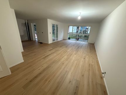 Un salon avec parquet et escalier menant au deuxième étage.