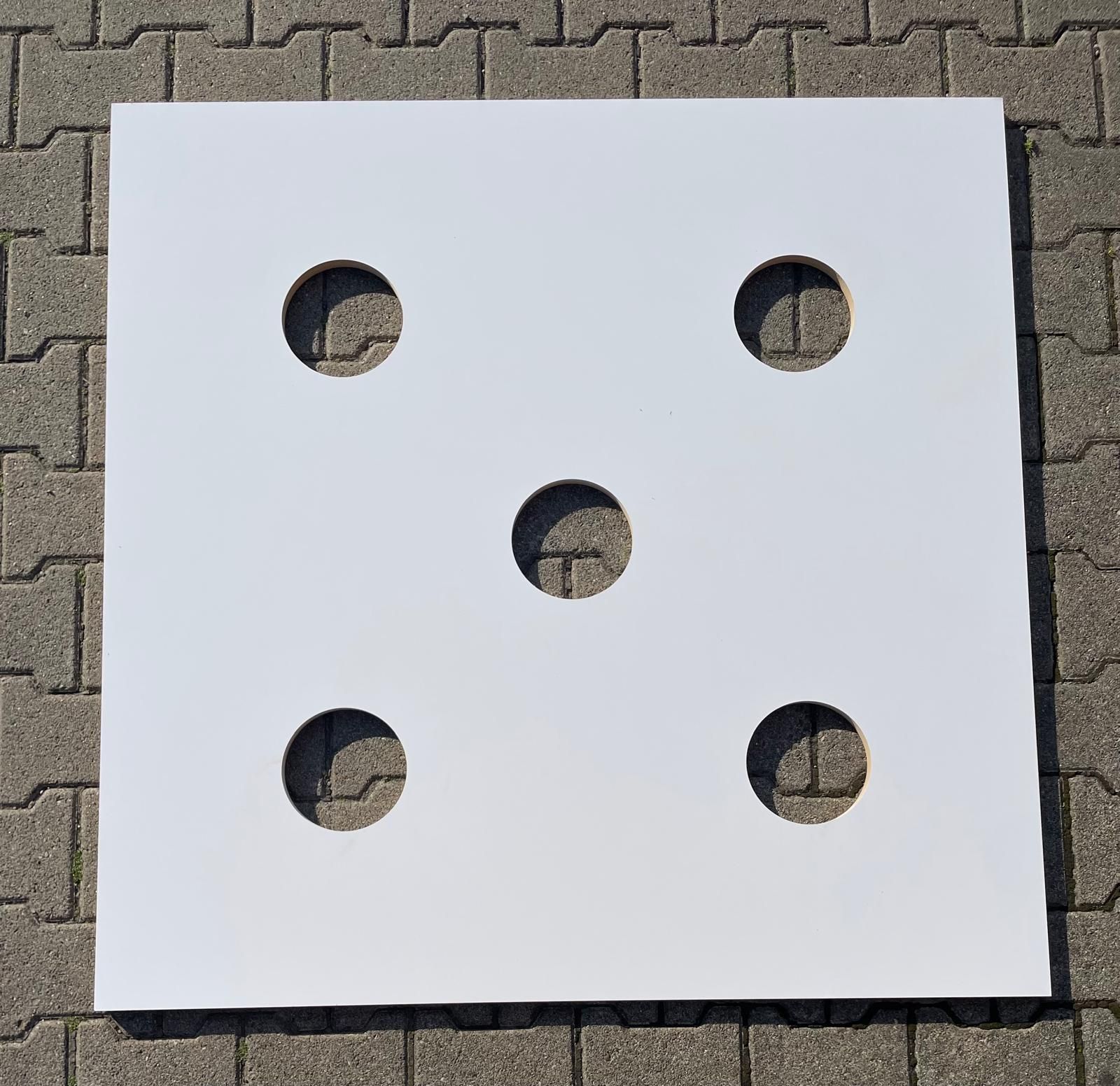 Auf einem gepflasterten Gehweg liegt ein weißes Quadrat mit Löchern.