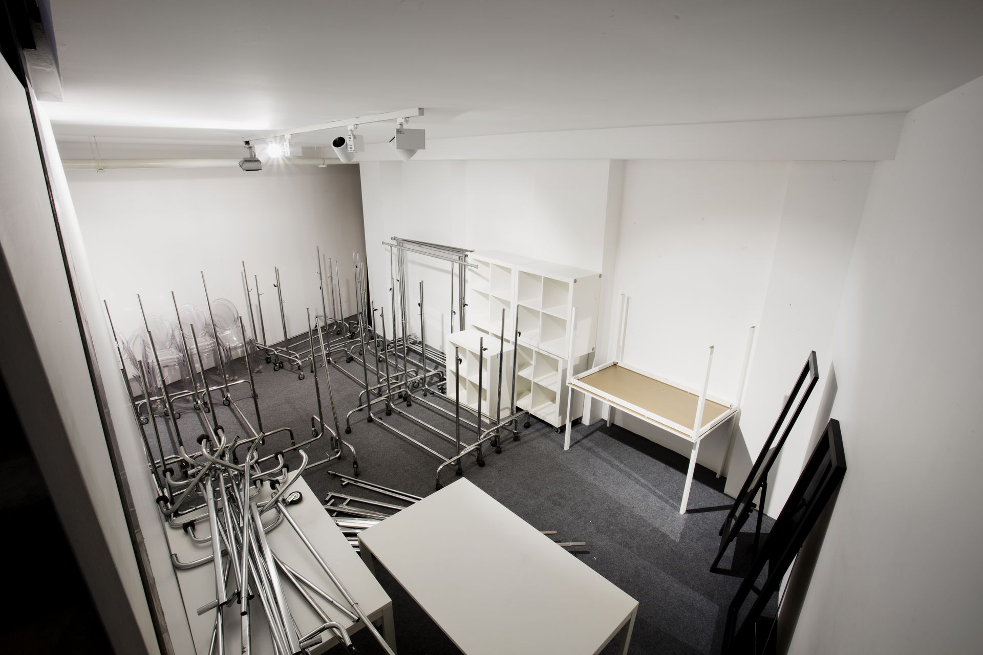 Pièce vide aux murs blancs, avec des portants à vêtements en métal.